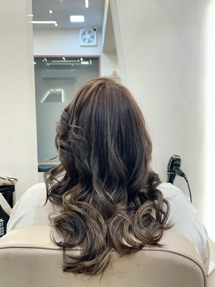 A beautiful hair color transformation styled into deep, glossy waves. The highlights are blended to create dimension and movement from the back.
