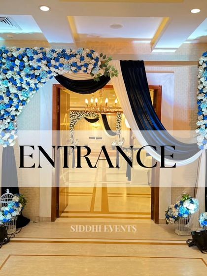 A sophisticated entrance featuring a floral arch of blue and white roses, complemented by deep blue and white drapery for a classic and serene welcome.