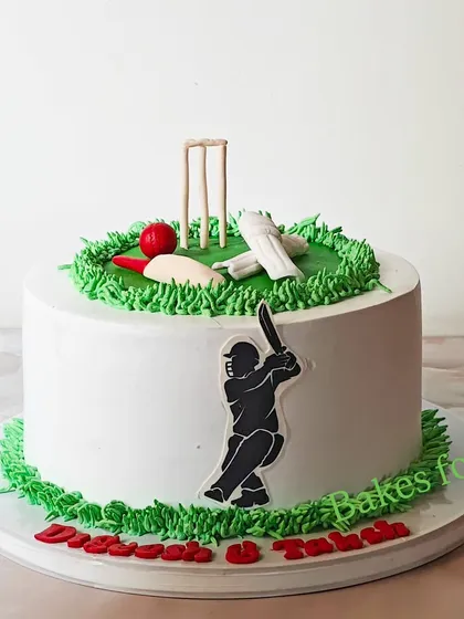 A classic cricket-themed cake with a pitch made of green buttercream, complete with wickets, a bat, and a ball.