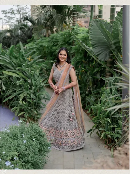 A beautiful solo portrait of the bride standing on a garden path. Her smile and elegant grey lehenga are the focus of this simple yet stunning shot.