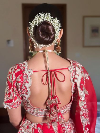 A classic bridal bun surrounded by a thick garland of baby's breath, perfect for a traditional red lehenga look.