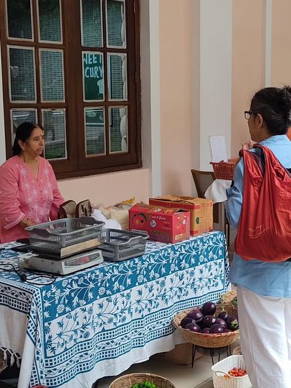 A customer with her reusable bags, shopping at a stall during difficult weather.
