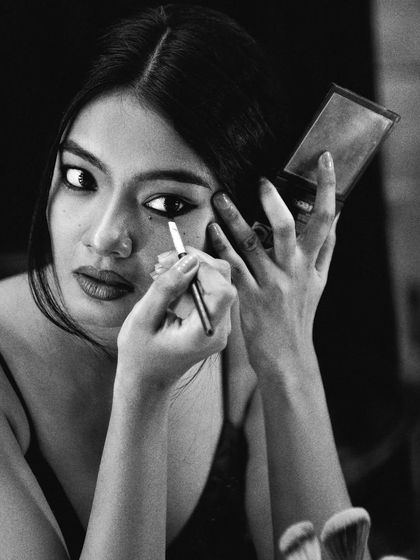 A focused, three-quarter view of the makeup application. The black and white tones emphasize the lines and shapes, from the curve of the eyeliner to the model's intense expression.