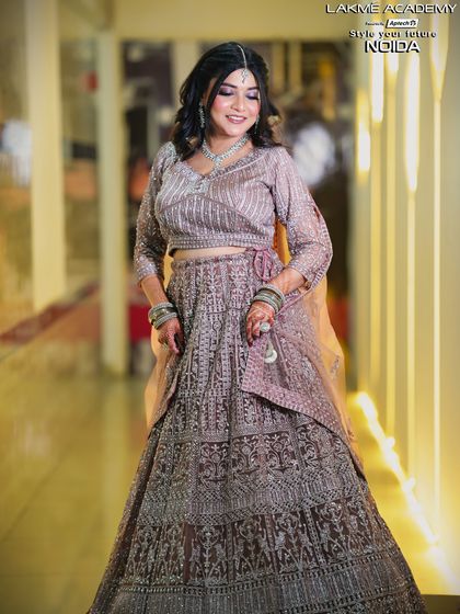 A full-length view of a student's work on an engagement look. The heavily embroidered lehenga is balanced with soft, shimmering makeup for a stunning result.