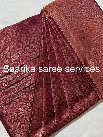 A maroon brocade saree, folded to protect its all-over pattern.