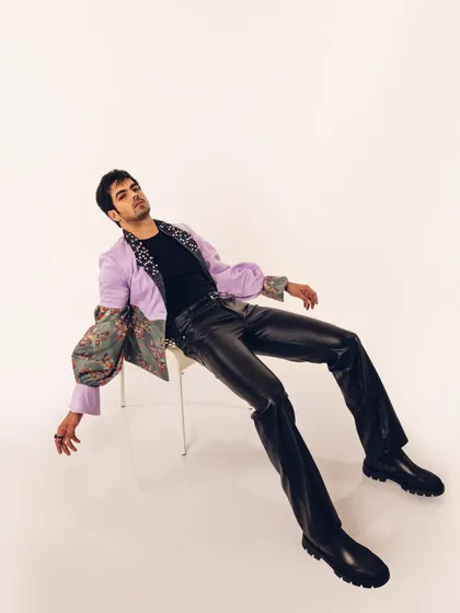 A relaxed, seated pose from the "Monsieur" lookbook. This styling shows how the avant-garde jacket can be worn, highlighting its unique construction and printed lapels.