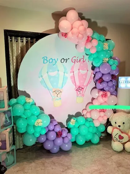A 'Boy or Girl' gender reveal party with a hot air balloon themed backdrop and a colorful balloon arch.
