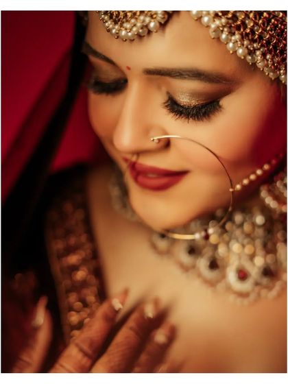 A stunning, intimate close-up of the bride, Vanshita, her eyes closed, highlighting her beautiful makeup and the texture of her skin.