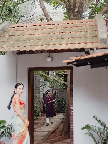 A bride looks back over her shoulder, framed by a white doorway and garden path, a lovely, candid-style portrait.
