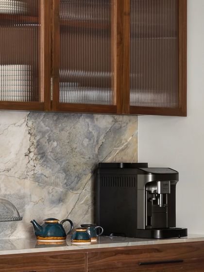 A detail from the West Coast Residence kitchen, where fluted glass cabinet doors and a beautiful marble backsplash add texture and refinement. The space is designed to be both a functional work area and a beautiful part of the home.