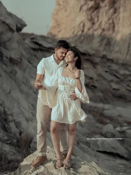 Set against a rugged, rocky landscape, this image captures a moment of tender connection. The natural light highlights their features and the soft textures of their outfits, creating a beautiful contrast that feels both adventurous and intimate. It’s a perfect example of an outdoor couple shoot.