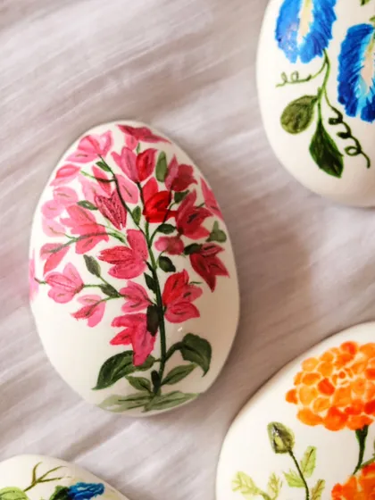 A close-up of a marzipan egg with a vibrant pink bougainvillea painting.