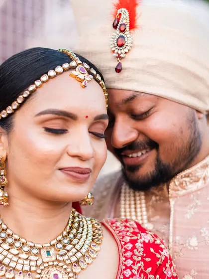 A close-up portrait that beautifully captures the intricate details of the bride's jewelry and makeup, and the couple's gentle affection.