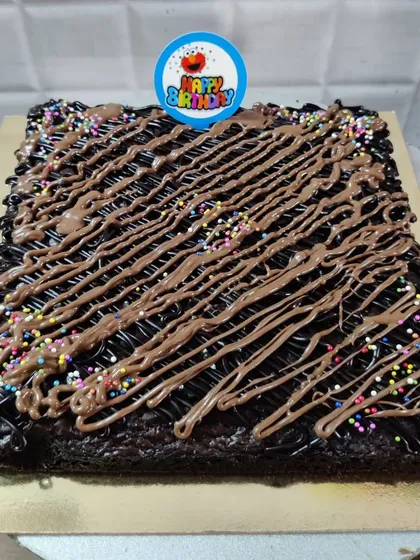 My brownies can also be turned into a celebration cake. This is a large, fudgy brownie slab decorated with chocolate drizzle, rainbow sprinkles, and a "Happy Birthday" topper.