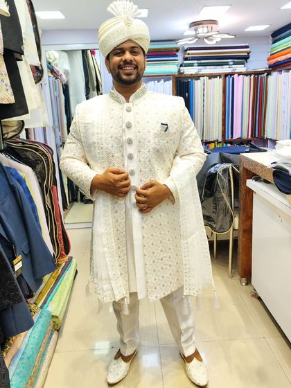 An all-white ensemble for the groom who loves elegance. This sherwani features delicate embroidery and is paired with a matching safa and stole with tassel details for a clean, cohesive look.