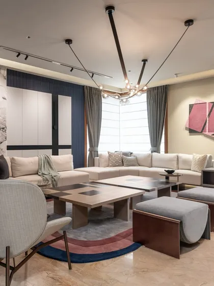The living area is designed for comfort and style, with a large sectional sofa and unique lighting. The mix of materials and the colorful rug add personality and warmth to the space.