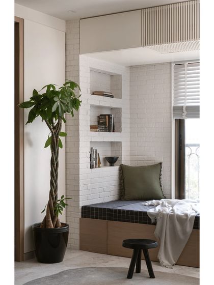 This versatile guest room features a daybed with built-in book niches and black plaid upholstery. The cozy reading nook is illuminated by a swinging wall light, making it a perfect spot for relaxation.