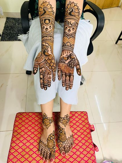 A full bridal set with matching designs for hands and feet. The hands feature peacock motifs, while the feet have a simpler, elegant pattern, creating a balanced look.