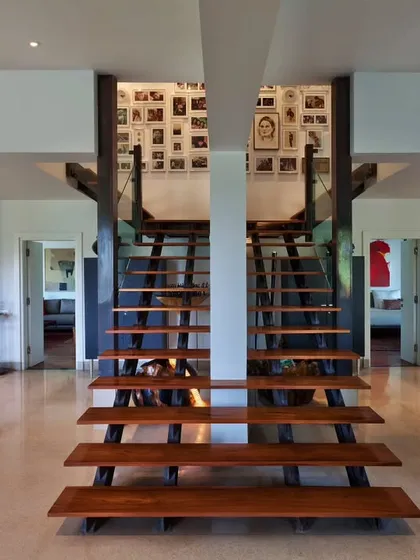 The symmetrical twin staircases at our Aishbagh holiday home, crafted from industrial metal girders and teak treads. This central architectural feature connects the home's private spaces while creating a powerful visual story of movement and memory.