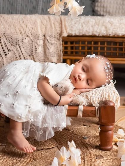 This little one is sleeping so peacefully in our dreamiest setup. The combination of the rustic wooden bench, jute rug, and delicate white flowers is just heavenly.