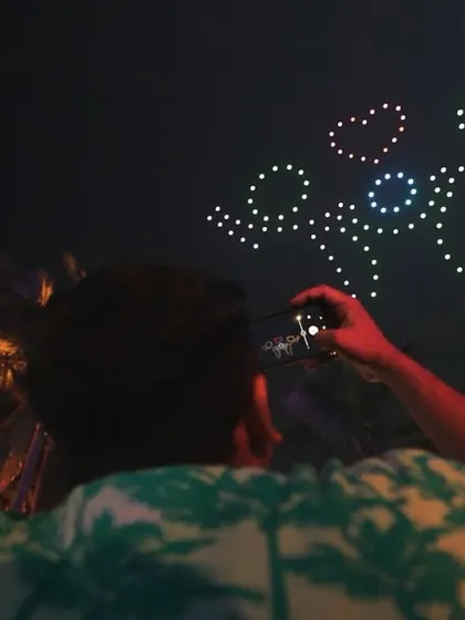A spectator captures a whimsical drone formation of stick figures, adding a touch of playfulness to the sophisticated celebration for Taj Hotels in Goa.