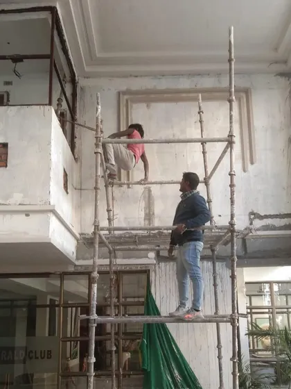 Workers on scaffolding, applying the initial layers of finish to the foyer of a luxury housing tower. This is a crucial step in preparing the surface for detailed architectural elements.