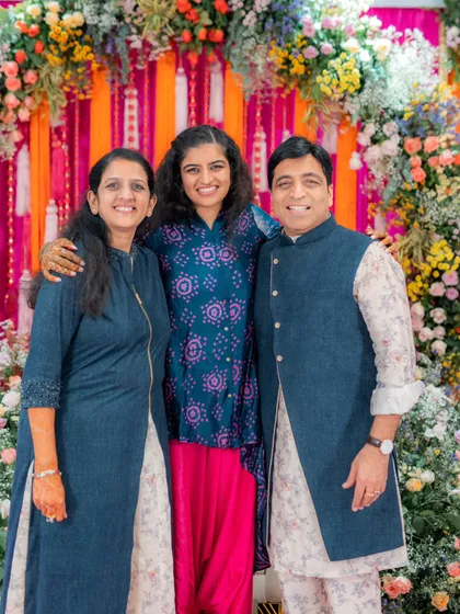A lovely portrait of the bride with her parents at the Mehendi. Their coordinated blue-toned outfits create a sense of harmony, with the father's printed kurta and vest adding a nice touch.