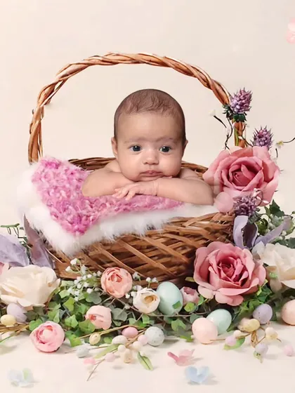 A sweet baby portrait in a wicker basket surrounded by pastel-colored flowers and Easter eggs. This is a perfect setup for a spring-themed photoshoot.