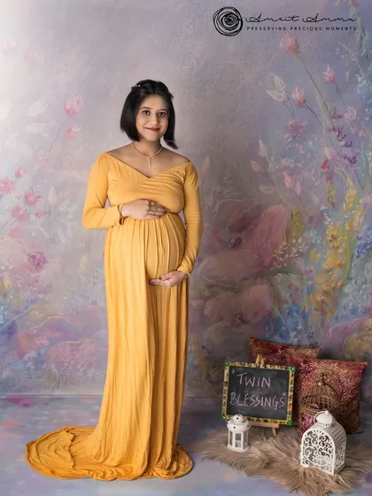 Announcing twin blessings! This mother to be glows in a beautiful yellow gown, with a small chalkboard sign sharing the exciting news.