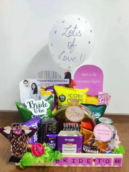 Here is a fun and vibrant hamper celebrating the bride-to-be. It's filled to the brim with her favorite snacks, chocolates, and cookies, complete with a personalized photo and a "Lots of Love" balloon to make her feel cherished as she counts down to her big day.