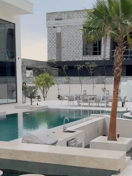 This wide shot shows the different zones we created: a poolside lounge, an outdoor bar and grill area, and a dining space, all unified by our simple and elegant planting scheme.
