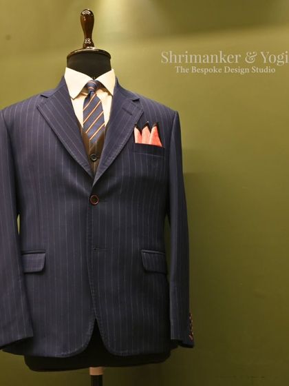 Another perspective of the classic navy pinstripe suit, this time with our studio logo. This composition reinforces our brand's commitment to timeless menswear and meticulous styling.