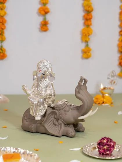 Lord Ganesha seated gracefully on an elephant, symbolizing the removal of obstacles with wisdom and strength. The contrast between the matte grey elephant and the shining silver idol creates a striking visual.