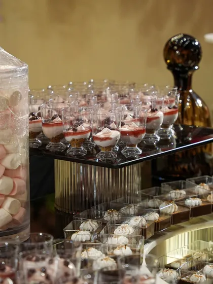 A beautiful dessert spread featuring trifles in crystal glasses, marshmallows, and delicate meringue bites.