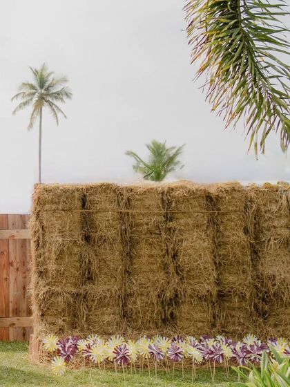 The outer wall of the hay maze, lined with colorful pinwheels. This small, playful detail adds a touch of whimsy to the rustic hay structure.