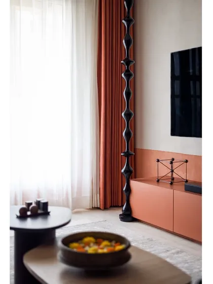 The TV wall features a modern, glossy black wooden turning that contrasts beautifully with the matte, textured wall.
