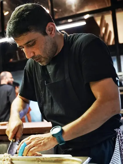 A chef concentrating as he prepares food in the kitchen. This candid shot offers an authentic glimpse into the hard work and precision behind the scenes of a restaurant.