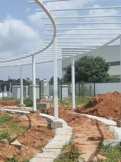 The curved steel framework for a long pergola being installed at Aamby City, Hoskote. This structure will eventually be covered in climbing plants.