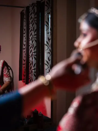 A close-up shot of the bride getting her makeup done, with the reflection in the mirror adding a creative touch.