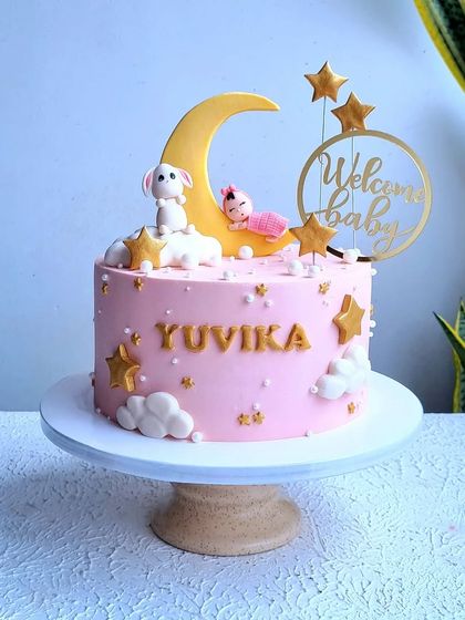 A full view of the "Welcome Baby" cake on its stand.