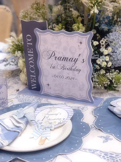 A personalized welcome sign and custom-designed place setting for Pramay's first birthday carnival.