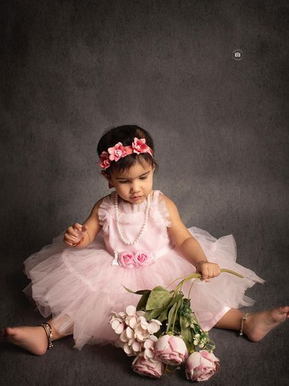 A quiet moment with a little one in a pink dress, looking down at a bouquet of flowers. A simple, sweet, and timeless baby portrait.