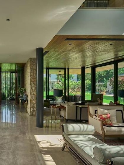 The interior living space of the 'Patio House' is defined by transparency, with floor-to-ceiling glass offering uninterrupted views of the garden.