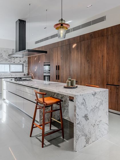 The full view of the kitchen wall, where floor-to-ceiling walnut cabinets provide ample storage and a dramatic backdrop to the stunning marble island.