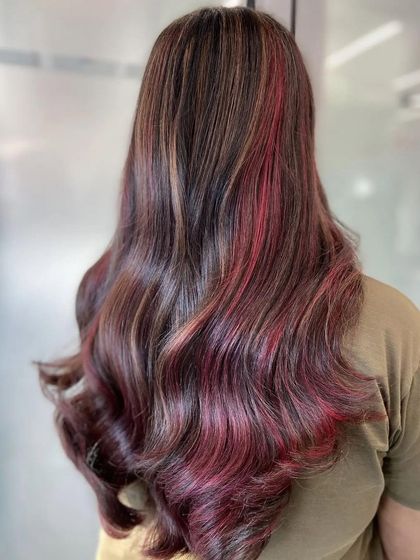 This look is a beautiful marriage of brown and red hair colors. I used a balayage technique to seamlessly blend the two shades, creating a playful yet sophisticated style with pops of red.