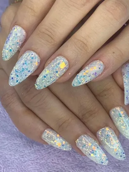 A fun and sparkly set of long nails with a translucent base and a mix of iridescent glitter flakes. This design gives a "confetti" or "broken glass" effect that is playful and unique.