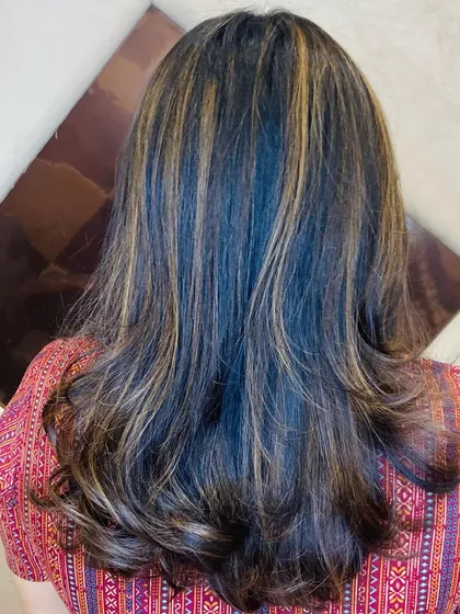 The back view of the client's layered cut and highlights, showing how the color is distributed throughout the hair for a natural, sun-kissed effect.