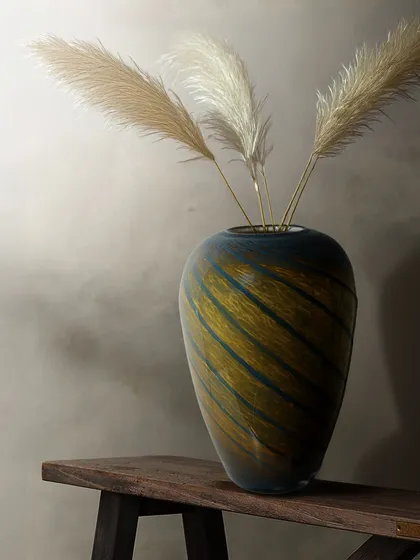 Styled with pampas grass, this blown glass vase with earthy, swirling stripes becomes a stunning decor element. It brings a sense of natural calm and artistic flair to any room.