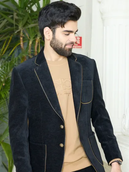 The luxurious texture of this black corduroy blazer is its main feature. The rich, velvety feel is complemented by subtle gold piping and elegant buttons, making it a timeless piece.