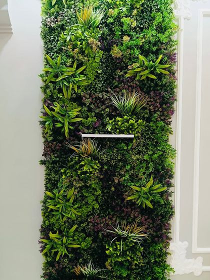 A close-up of a mixed foliage panel installed indoors. The different types of artificial plants create depth and realism, making the wall a captivating feature.
